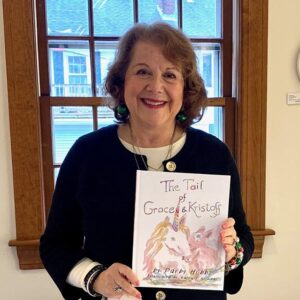 A smiling woman (Darby Hobbs) holding her book The Tale of Grace & Kristoff